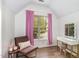 Attic bedroom with pink curtains, sloped ceiling, a makeup vanity, and a chair with accent pillow at 1209 Shasta Daisy Dr, Wake Forest, NC 27587