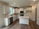 Bright kitchen featuring white cabinetry, stainless steel appliances, quartz countertops, and an island at 1252 Randwick Vly Ct, Zebulon, NC 27597
