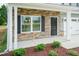 Inviting front porch with stone facade, black door, and landscaped garden at 127 High Hampton Way, Fuquay Varina, NC 27526