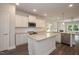 Modern kitchen featuring white cabinetry, granite island, and open-concept design to living area at 127 High Hampton Way, Fuquay Varina, NC 27526