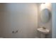 Well-lit powder room with pedestal sink, round mirror, and modern fixtures at 127 High Hampton Way, Fuquay Varina, NC 27526
