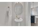 A modern half bathroom featuring a pedestal sink, gold faucet, decorative mirror, and white walls at 1272 Brown Velvet Ln, Apex, NC 27523