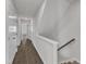 Hallway with wood floor, white walls, with multiple white doors and railing leading to the stairs at 1272 Brown Velvet Ln, Apex, NC 27523