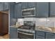 Modern kitchen featuring stainless steel appliances, granite countertops, gray cabinets, and under-cabinet lighting at 1272 Brown Velvet Ln, Apex, NC 27523