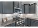 Close-up of kitchen with stainless steel appliances, gray cabinets, and granite countertops with white subway tile backsplash at 1272 Brown Velvet Ln, Apex, NC 27523