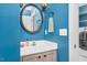 Bright half bathroom with blue wall, framed mirror, light vanity, and modern fixtures at 1576 Cheves Rd, Zebulon, NC 27597