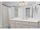 This bathroom features a large mirror, a floral shower curtain, and light-colored cabinets at 1576 Cheves Rd, Zebulon, NC 27597