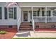 Inviting front porch with brick stairs, white railings, and dark green shutters, creating a cozy entrance at 1576 Cheves Rd, Zebulon, NC 27597