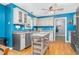 Bright kitchen with stainless steel appliances, an island, wooden floors, and blue walls at 1576 Cheves Rd, Zebulon, NC 27597