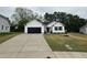 A white one-story home with a black garage door, concrete driveway, and grassy front yard at 163 Oakfield Trace Dr, Four Oaks, NC 27524