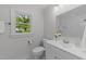 Bright bathroom showcasing a white vanity, classic fixtures, and a window view to the backyard at 1809 Glendale Ave, Durham, NC 27701