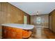 View of living room with hardwood floors, wood-paneled walls, built-in cabinet, and natural light at 2021 Bundy Ave, Durham, NC 27704