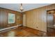 Living room with hardwood floors, wood-paneled walls, vintage lighting, and a bright window at 2021 Bundy Ave, Durham, NC 27704