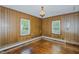 Living room with hardwood floors, wood-paneled walls, vintage lighting, and natural light at 2021 Bundy Ave, Durham, NC 27704