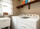 Bright laundry room with washer, dryer, utility sink, and wooden storage shelves at 204 Wiley Oaks Dr, Wendell, NC 27591