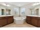 Bathroom with a corner tub between two vanities, each featuring a mirror and natural light through two windows at 205 Begen St, Morrisville, NC 27560