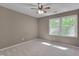 Neutral carpeted bedroom featuring a ceiling fan and window with a view of trees at 225 Bay Dr, Cary, NC 27511