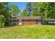 Exterior view of a brick home with a covered parking area, mature trees, and a grassy lawn at 2500 Courtland Dr, Sanford, NC 27330