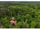 Expansive aerial view of wooded acreage surrounding a home with a striking red roof; serene and secluded at 2917 Ericka Dr, Hillsborough, NC 27278