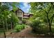 Multi-level home surrounded by lush greenery, with a rustic wood exterior and scenic garden path at 2917 Ericka Dr, Hillsborough, NC 27278