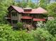 Attractive multi-level home with a red roof surrounded by lush green trees and shrubbery at 2917 Ericka Dr, Hillsborough, NC 27278
