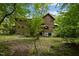 Rear view of wood home surrounded by lush foliage, showcasing its natural setting at 2917 Ericka Dr, Hillsborough, NC 27278