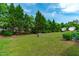 The lush backyard features a grassy lawn, mature trees, and a satellite dish for outdoor enjoyment at 3148 Rapid Falls Rd, Cary, NC 27519