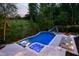 Backyard oasis with a pool, slide, in-pool loungers, and lush greenery overlooking a vineyard at 3215 Bellamy Ridge Dr, Apex, NC 27523