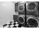Well-organized laundry room featuring stacked washer and dryer, black and white tile, and sleek cabinets at 3215 Bellamy Ridge Dr, Apex, NC 27523