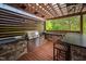 Well-equipped outdoor kitchen with built-in grill, stone accents, bar seating and wooden pergola at 3215 Bellamy Ridge Dr, Apex, NC 27523