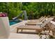 Poolside view with modern lounge chairs, a slide, and lush landscaping creates a relaxing oasis at 3215 Bellamy Ridge Dr, Apex, NC 27523