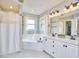 Bright bathroom with double vanity, tub and shower combo, and large mirrors at 3809 Victorian Grace Ln, Apex, NC 27539