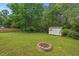 Home's lush backyard featuring a fire pit, storage shed, and mature landscaping at 3902 Booker Ave, Durham, NC 27713
