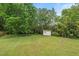 Home's green backyard featuring a fire pit, storage shed, and mature landscaping at 3902 Booker Ave, Durham, NC 27713