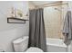 Cozy bathroom features a shower-tub combo with stylish curtain and modern floating shelf at 3902 Booker Ave, Durham, NC 27713