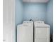 Functional laundry room with a white washer and dryer, and clean blue walls at 3902 Booker Ave, Durham, NC 27713