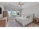Relaxing main bedroom features tray ceiling, ceiling fan, a plush bed, and exterior views at 400 Chickasaw Plum Dr, Holly Springs, NC 27540