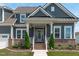Charming home featuring gray siding, brick accents, a covered porch, and manicured landscaping in the front yard at 400 Chickasaw Plum Dr, Holly Springs, NC 27540