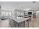 A modern kitchen features an island with seating, stainless steel appliances, and an open floor plan to the living area at 400 Chickasaw Plum Dr, Holly Springs, NC 27540