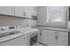 Modern laundry room with front-load machines, white cabinets, and a countertop at 400 Chickasaw Plum Dr, Holly Springs, NC 27540