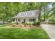 Charming home with a covered front porch, dormer windows, lush landscaping, and a brick chimney on the side at 404 Trappers Run Dr, Cary, NC 27513