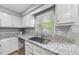 A stainless steel sink sits under a window with white cabinets and speckled granite countertops at 404 Trappers Run Dr, Cary, NC 27513