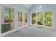 Bright sunroom featuring floor-to-ceiling windows and access to a wooden deck with lush greenery views at 4041 Brook Cross Dr, Apex, NC 27539