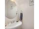 Powder room with a stylish round mirror and a white pedestal sink at 412 Stone Flower Ln, Raleigh, NC 27603