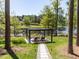 Scenic backyard with a stone pathway leading to a pergola overlooking a tranquil lake, perfect for relaxation at 4521 Briarglen Ln, Holly Springs, NC 27540