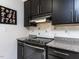 A kitchen showcasing black cabinets, granite countertops, a tiled backsplash, and a stainless steel oven range at 4521 Briarglen Ln, Holly Springs, NC 27540