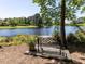 Inviting lakeside bench with a decorative potted plant, perfect for enjoying the peaceful and picturesque water views at 4521 Briarglen Ln, Holly Springs, NC 27540