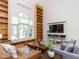 Bright living room with large window, hardwood floors, custom built-in bookshelves, and modern furniture at 4521 Briarglen Ln, Holly Springs, NC 27540