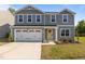 Two-story home with a two-car garage, vinyl siding, tidy landscaping, and a welcoming yellow front door at 473 Lavatera Dr, Wendell, NC 27591