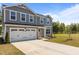Two-story home with attached two-car garage, vinyl siding, long driveway, and manicured lawn at 473 Lavatera Dr, Wendell, NC 27591